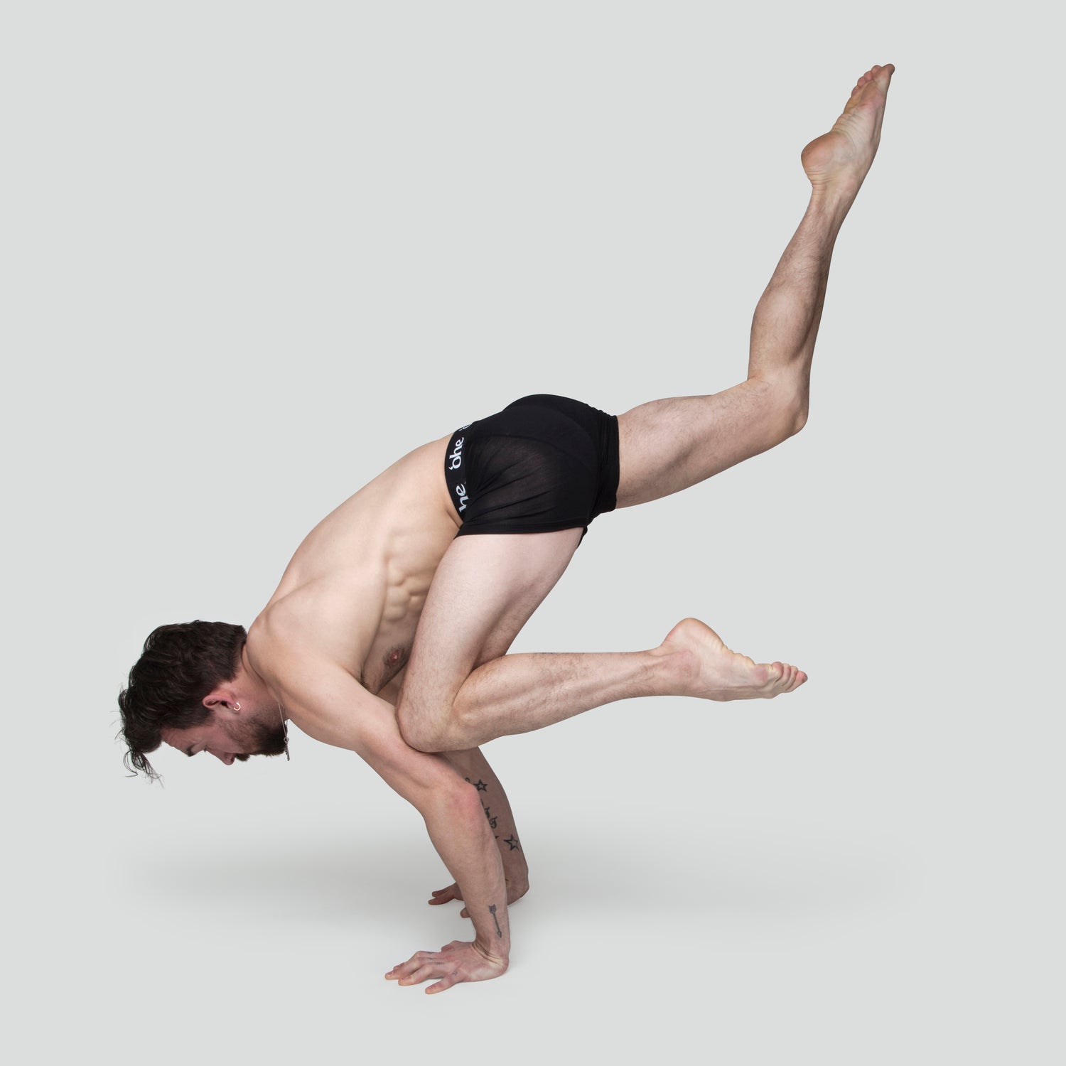 A sporty man doing a yoga pose wearing a pair of charcoal coloured 'ohe underwear